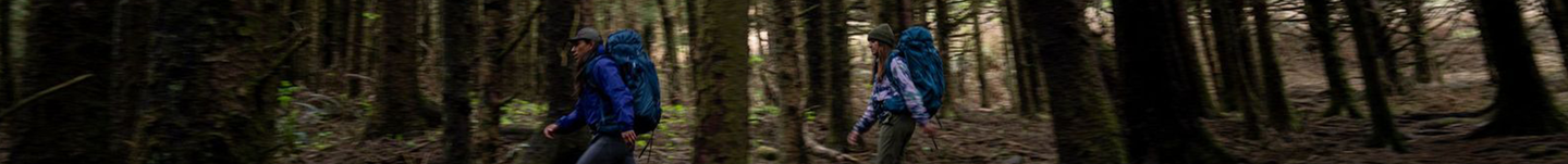 Image is of two hikers wearing the Baltoro and Deva packs in the woods.